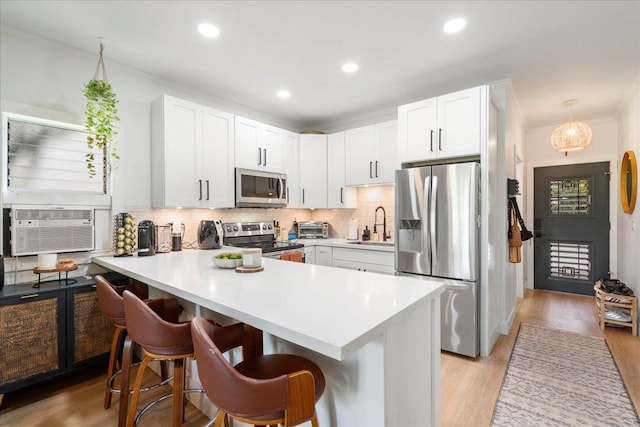 4435 Lower Honoapiilani Rd Unit 142, Lahaina, HI 96761 - kitchen featuring stainless steel appliances, a peninsula, decorative backsplash, a kitchen bar, and white cabinetry