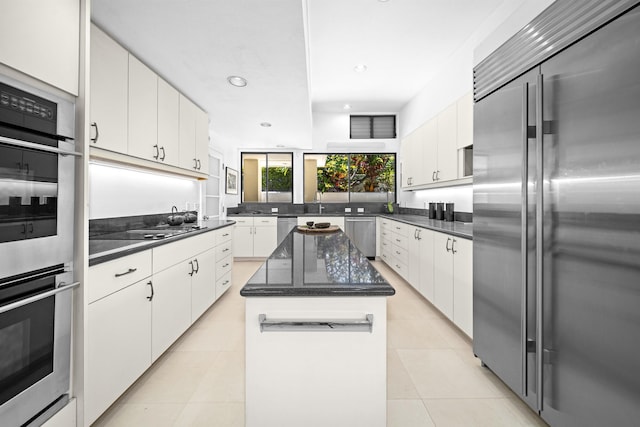 kitchen featuring stainless steel appliances, white cabinetry, light tile patterned flooring, a center island, and recessed lighting