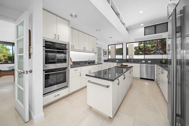 kitchen with stainless steel appliances, plenty of natural light, dark countertops, a center island, and recessed lighting