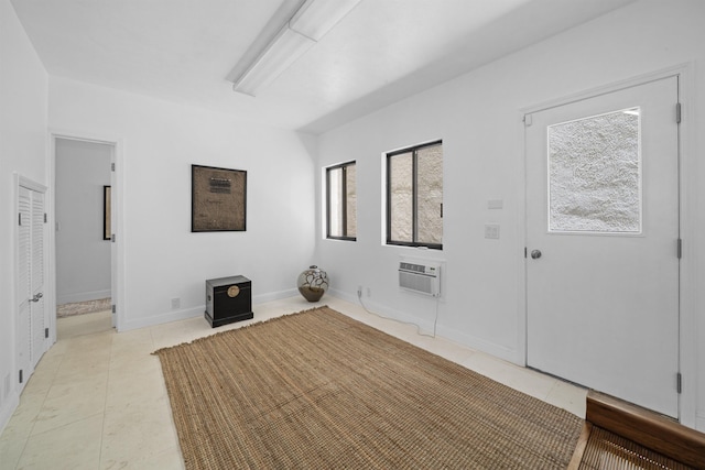 foyer with plenty of natural light, an AC wall unit, light tile patterned flooring, and baseboards