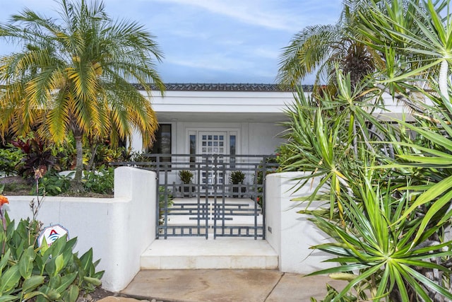 view of exterior entry featuring a porch, fence, and a gate