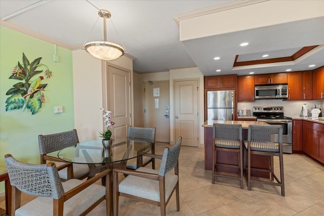 dining space featuring light tile patterned floors, a tray ceiling, and ornamental molding