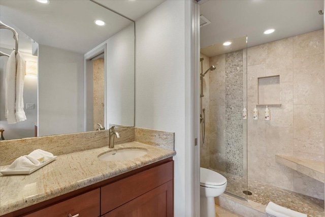 bathroom with toilet, vanity, and tiled shower