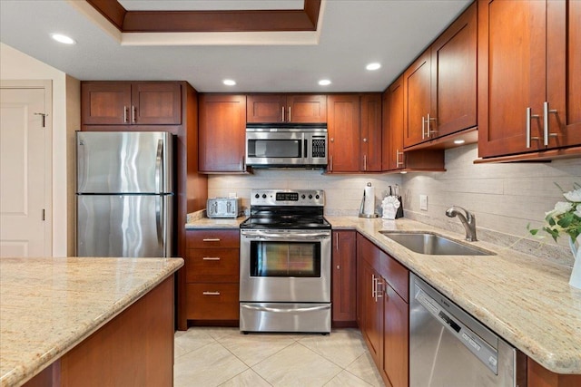 kitchen with light stone countertops, appliances with stainless steel finishes, a raised ceiling, and sink