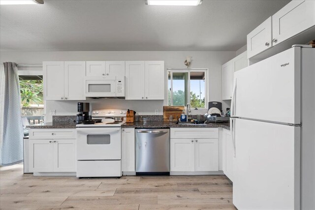 kitchen featuring a sink, white cabinets, light wood finished floors, and white appliances