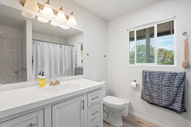 full bathroom with toilet, baseboards, wood finished floors, and vanity
