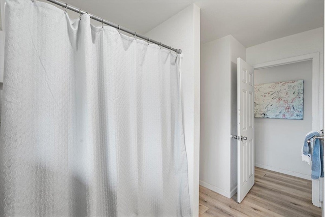 full bathroom featuring baseboards and wood finished floors
