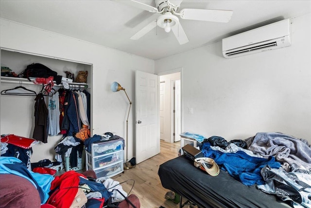 bedroom with light wood-type flooring, ceiling fan, a wall mounted AC, and a closet