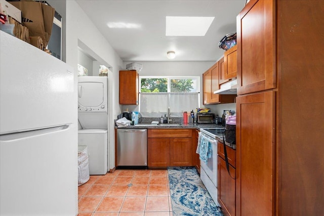 kitchen with stacked washer / dryer, a skylight, brown cabinets, a sink, and white appliances