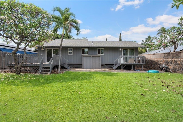 back of house with fence, a lawn, a wooden deck, and stairs