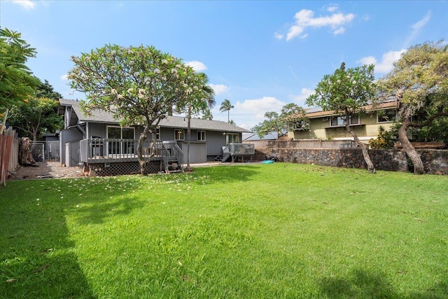 rear view of house with a lawn, fence, and a deck