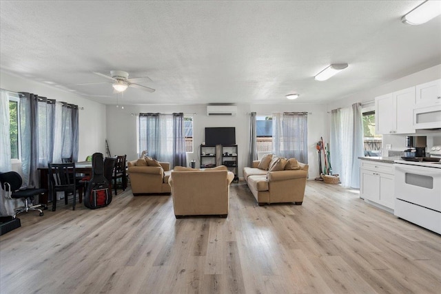 living area with a healthy amount of sunlight, ceiling fan, an AC wall unit, and light wood-type flooring