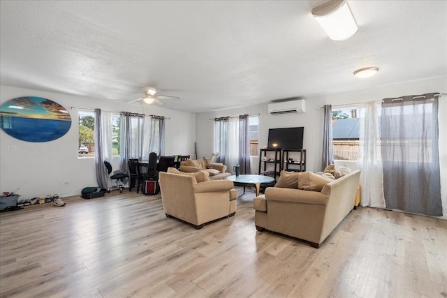 living room featuring plenty of natural light, a wall mounted AC, and light wood-type flooring