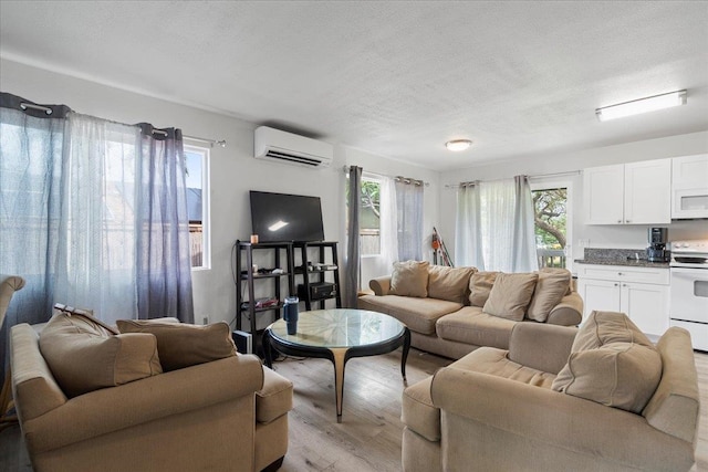 living room featuring light wood-style floors, a textured ceiling, and a wall mounted AC