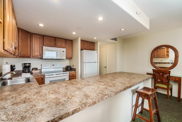 kitchen with sink, kitchen peninsula, a kitchen bar, and white appliances