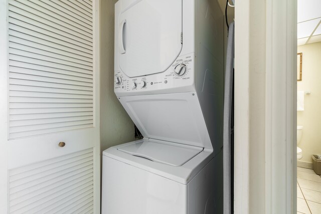 laundry room with stacked washer / drying machine and light tile patterned floors