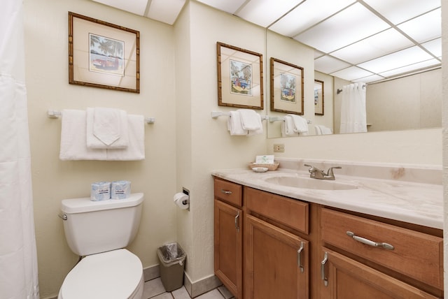 bathroom with a paneled ceiling, toilet, vanity, and tile patterned floors