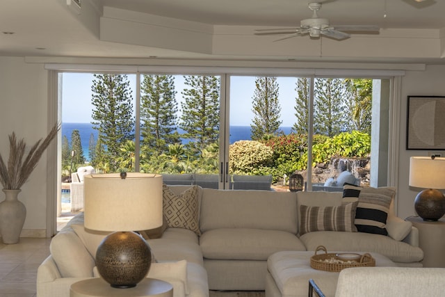 living room with a water view, light tile patterned floors, and a ceiling fan