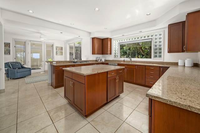 kitchen with light tile patterned floors, a peninsula, a kitchen island, and light stone countertops