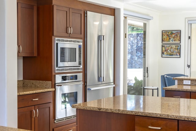 kitchen featuring crown molding, appliances with stainless steel finishes, light stone countertops, and brown cabinets