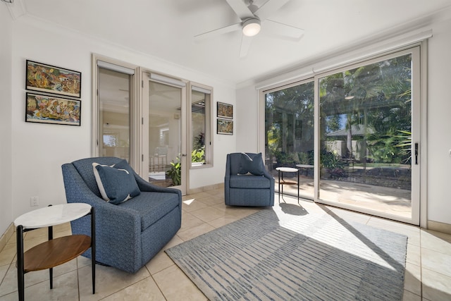 living area featuring a ceiling fan, crown molding, baseboards, and light tile patterned floors