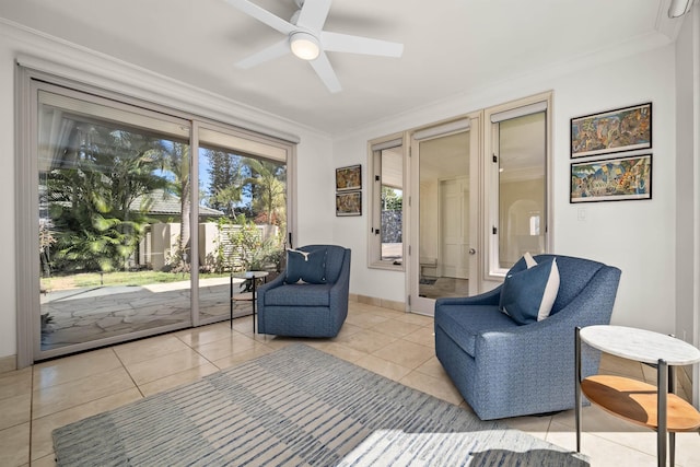 living area with light tile patterned floors, ornamental molding, a ceiling fan, and baseboards