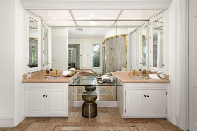 bathroom with a stall shower, two vanities, a sink, and visible vents