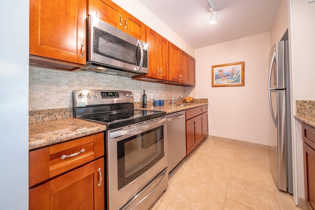 kitchen featuring light tile patterned flooring, sink, light stone counters, stainless steel appliances, and backsplash