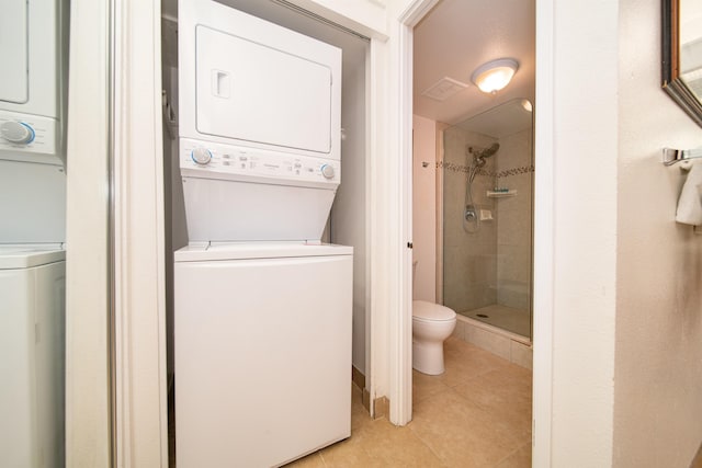 laundry area with stacked washer and dryer and light tile patterned floors