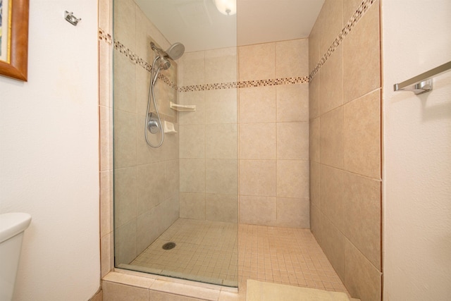 bathroom with a tile shower and toilet