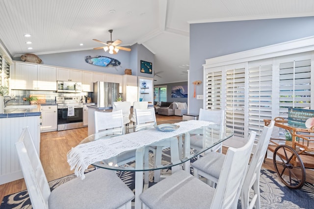 dining space featuring lofted ceiling, light wood-style flooring, ceiling fan, and crown molding