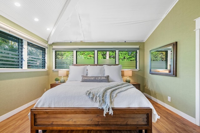 bedroom featuring lofted ceiling, multiple windows, and light wood-style flooring