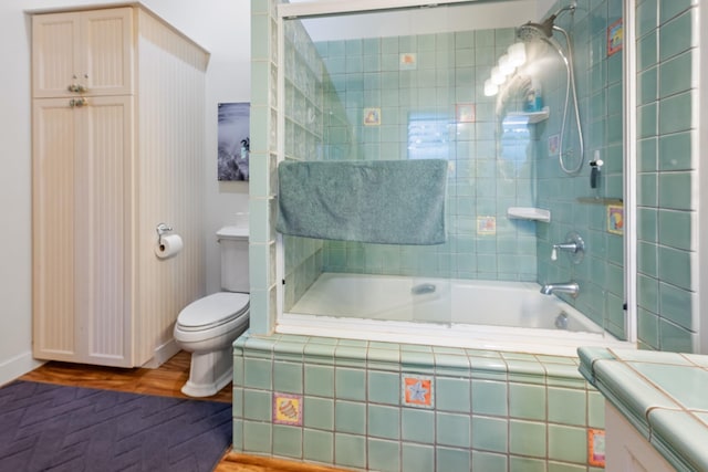 full bathroom featuring tiled shower / bath, toilet, and wood finished floors