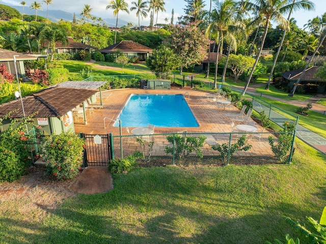 community pool with fence, a patio, and a lawn