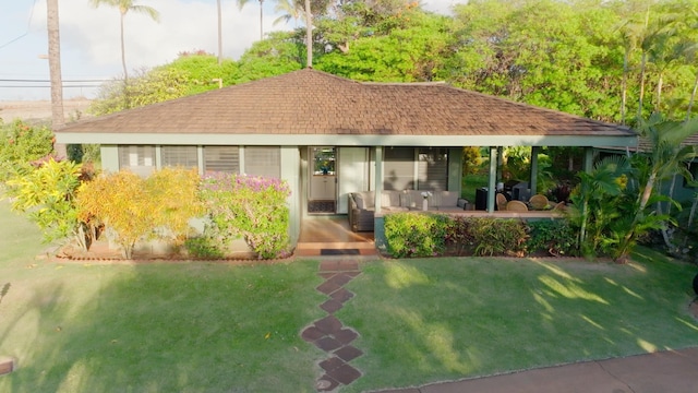 exterior space featuring a shingled roof, a front yard, and a patio area