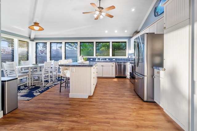 kitchen with appliances with stainless steel finishes, a breakfast bar, a center island, white cabinetry, and pendant lighting