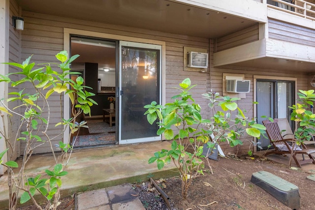 view of exterior entry with a patio and an AC wall unit