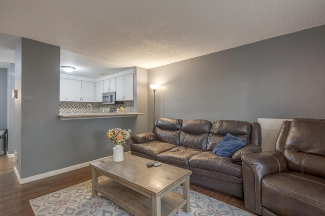 living area featuring a textured ceiling, wood finished floors, and baseboards