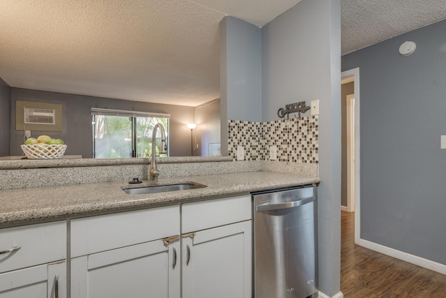 kitchen featuring a sink, decorative backsplash, dark wood-type flooring, stainless steel dishwasher, and a textured ceiling