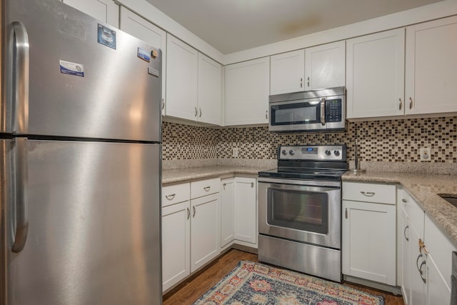 kitchen with decorative backsplash, stainless steel appliances, and white cabinets