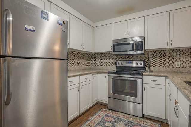 kitchen with white cabinetry, stainless steel appliances, and dark wood finished floors
