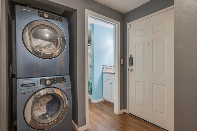 laundry area with stacked washer / dryer and wood-type flooring