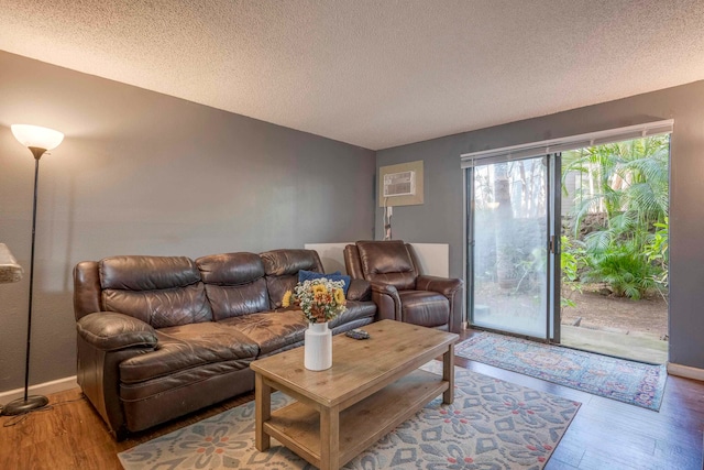 living room featuring a wall mounted air conditioner, hardwood / wood-style floors, and a textured ceiling