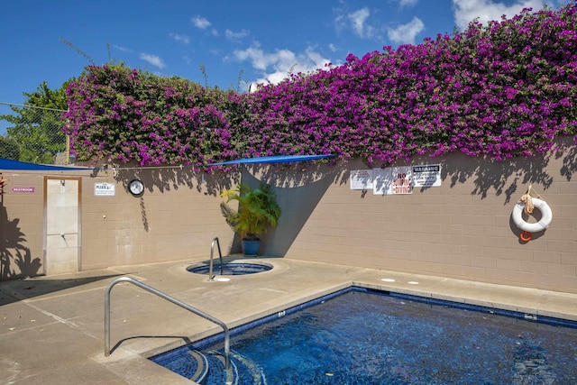 pool with a patio area, an in ground hot tub, and fence