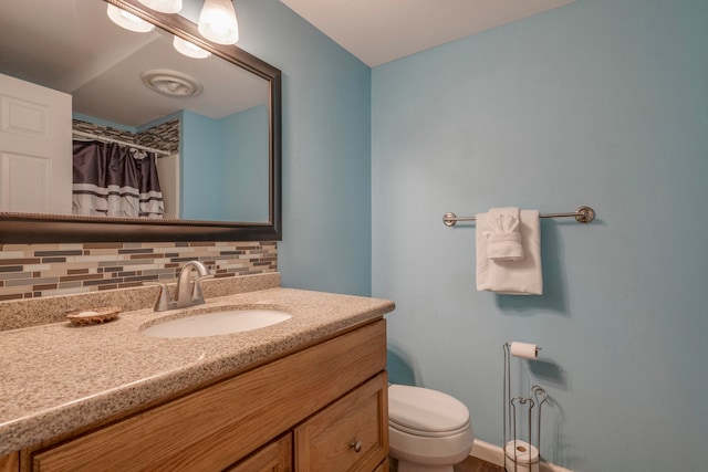 bathroom with vanity, walk in shower, toilet, and backsplash