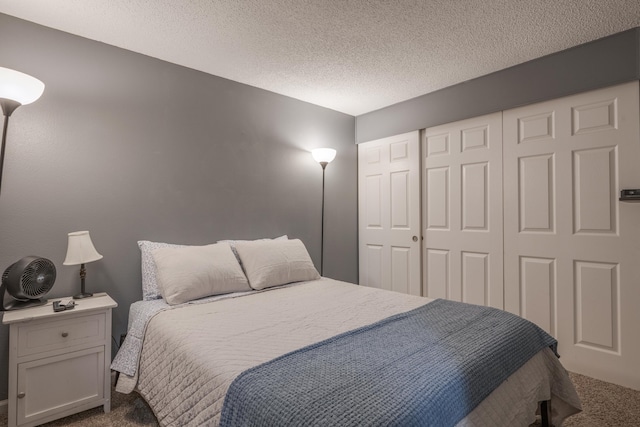 bedroom featuring a textured ceiling, a closet, and dark colored carpet
