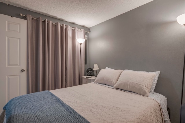 bedroom with lofted ceiling and a textured ceiling