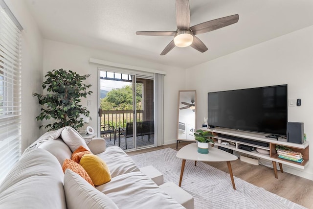 living area with baseboards, ceiling fan, and wood finished floors
