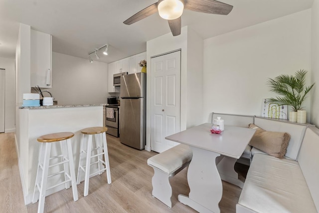 dining area with light wood-style floors, a ceiling fan, and rail lighting