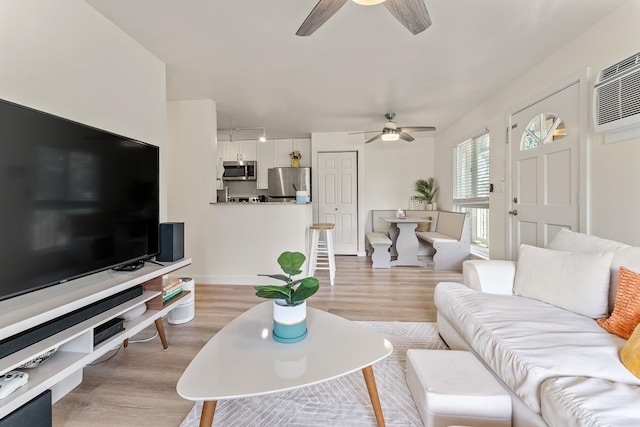 living room featuring baseboards, ceiling fan, and light wood-style flooring